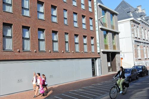 a group of people walking down a street next to a building at Residentie Alfa Inn*** in Blankenberge