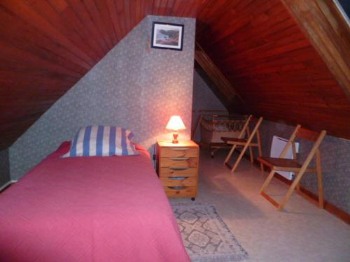 1 dormitorio con cama rosa, mesa y sillas en P'ty gîte de Bréharadec, en Goulien
