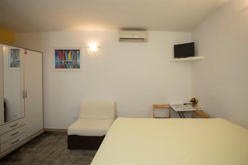 1 dormitorio con 1 cama blanca y 1 silla en Room Dioklecijan, en Split