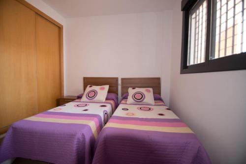 アグアドゥルセにあるapartamento aguadulce playa con WIFIの紫のシーツが備わる客室内のベッド2台
