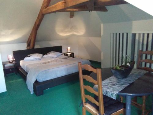 une chambre avec un lit et une table avec une chaise dans l'établissement la longere de Lor'Phée, à Chantepie