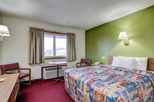 a hotel room with a bed and a desk and a window at Bloomer Inn & Suites in Bloomer