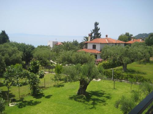a garden with trees and a house in the background at Petradaki Apartments in Mola Kalyva