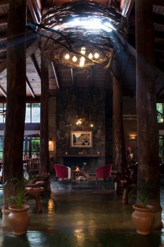 a living room with a fireplace and a stone wall at La Aldea De La Selva Lodge in Puerto Iguazú