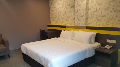 a bedroom with a white bed with a phone next to it at Kampar Boutique Hotel in Kampar