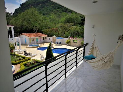 a hammock on the balcony of a house with a pool at Hotel Campestre Santa Catalina in San Gil
