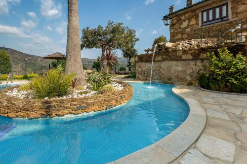 a swimming pool in a backyard with a stone wall and a resort at Casa da Encruzilhada in Ponte de Lima