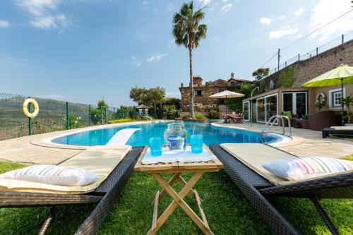 a swimming pool with a table and chairs next to a house at Casa da Encruzilhada in Ponte de Lima