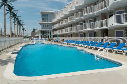 a swimming pool in front of a hotel with lounge chairs at Shalimar Resort in Wildwood Crest