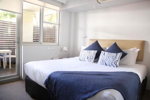 um quarto com uma cama grande e almofadas azuis e brancas em The Blenheim em Sydney