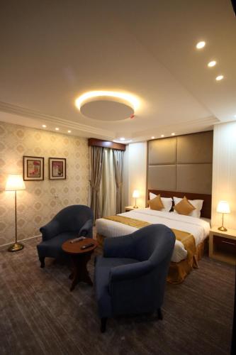 a hotel room with a bed and two chairs at Ra'af Abha lilwahadat alsakaniih راف أبها للوحدات السكنية in Abha