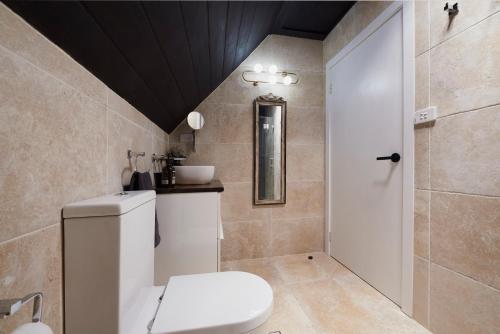 a bathroom with a white toilet and a black ceiling at Church Conversion in Robertson