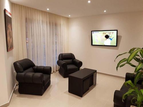 a living room with two chairs and a flat screen tv at Hotel Firenze in Necochea