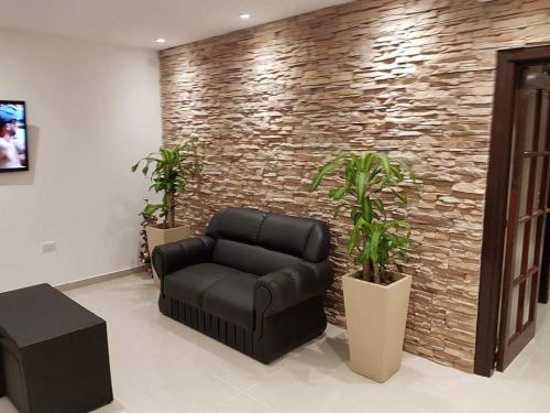 a black leather couch in a room with a brick wall at Hotel Firenze in Necochea