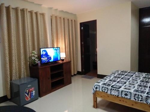 a room with a bed and a tv on a cabinet at Lourdes Inn in Manila