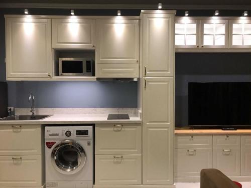 a kitchen with white cabinets and a washing machine at Blu Thew Talay Estate Hua Hin in Phetchaburi