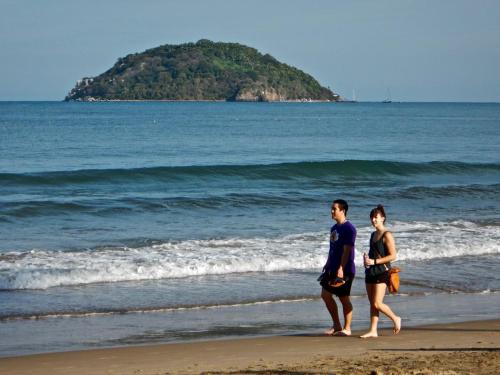 a man and a woman walking on the beach at Bungalows Maria Teresa in Rincon de Guayabitos