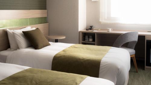 a hotel room with two beds and a desk at Nest Hotel Hakata Station in Fukuoka