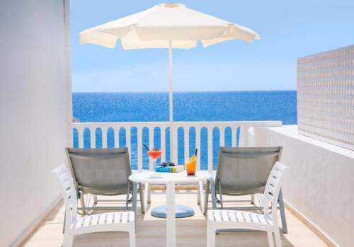 a table with two chairs and an umbrella on a balcony at Hotel Sunshine in Kamari