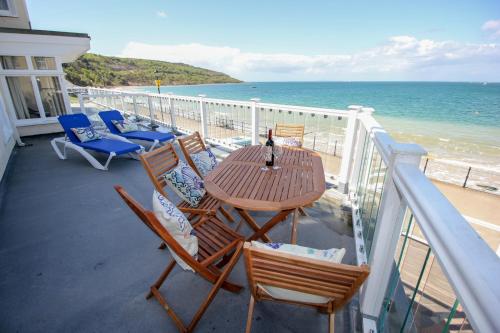 a table and chairs on a balcony overlooking the beach at Garden Apartment, 1 Pilots Point in Totland
