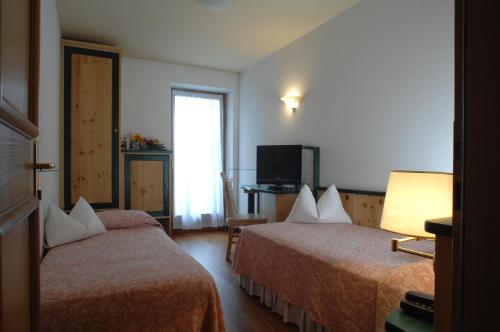 a hotel room with two beds and a television at La Roccia Wellness Hotel in Cavalese
