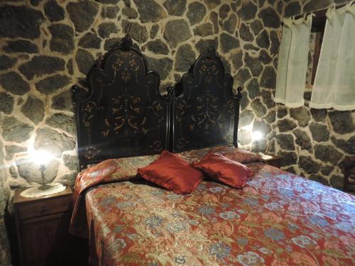 a bed with two pillows on it in a stone room at Rural House Etna in Castiglione di Sicilia