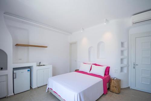 a white bedroom with a bed with pink and white pillows at Anais in Mýkonos City