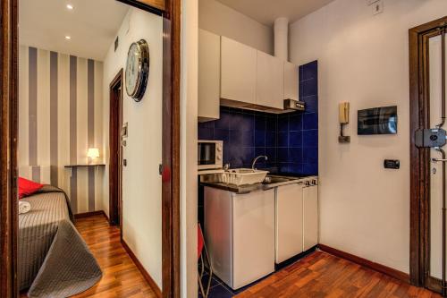 a kitchen with white cabinets and a blue wall at M&L Apartments - Ardesia Colosseo in Rome