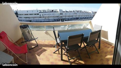 a balcony with a table and chairs and a cruise ship at Heliopolis in Cap d'Agde