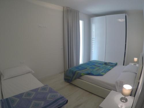 ein kleines weißes Schlafzimmer mit einem Bett und einem Fenster in der Unterkunft Mare Incanto - Agenzia Cocal in Caorle