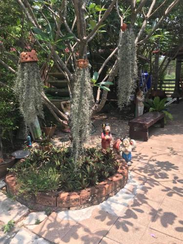 a tree in a garden with some plants at Green Leaf Resort in Surin