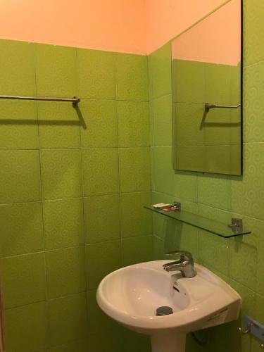 a green bathroom with a sink and a mirror at Green Leaf Resort in Surin