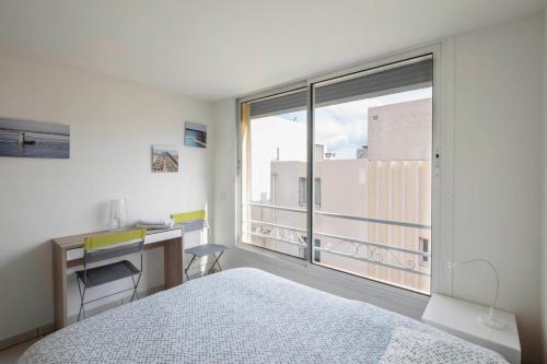 une chambre avec un lit, un bureau et une fenêtre dans l'établissement Coup de coeur: duplex centre ville vue mer & port, à Bandol