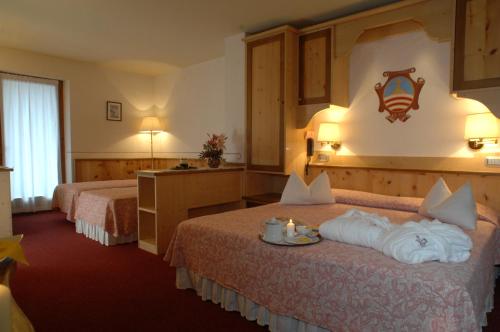 a hotel room with two beds with towels on them at La Roccia Wellness Hotel in Cavalese