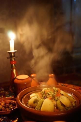 a bowl of food on a table with a candle at Berber Family Lodge in Imlil