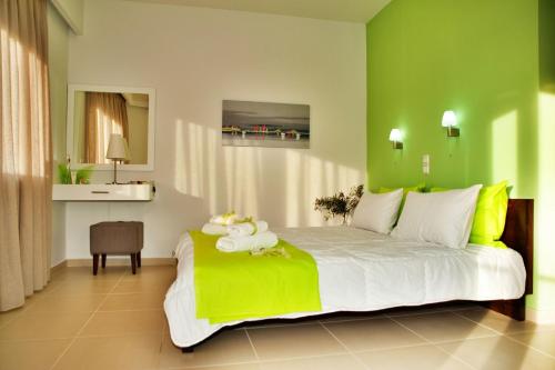 - une chambre avec un grand lit et un mur vert dans l'établissement Esthisis Suites Chania, à Platanias