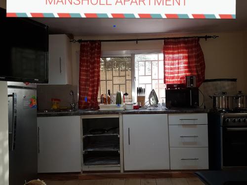 a kitchen with white cabinets and a window at Mansholl Luxurious Apartment in Freetown