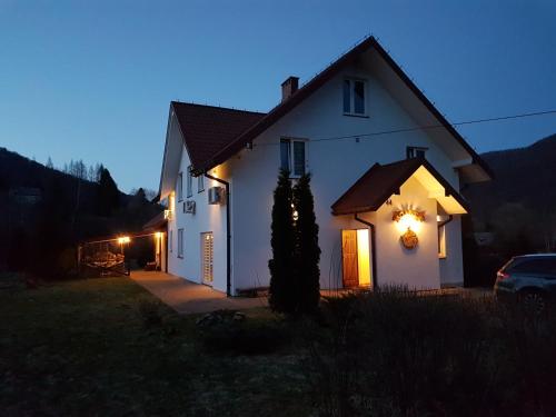 Una casa blanca con luces en el costado. en Konie2 Pokoje Gościnne, en Wetlina