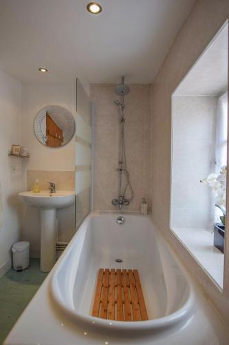 La salle de bains est pourvue d'une grande baignoire blanche et d'un lavabo. dans l'établissement La Maison Muguet, à Civray