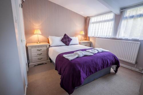 a bedroom with a bed with purple sheets and two lamps at The Hotel Balmoral - Just for Adults in Torquay