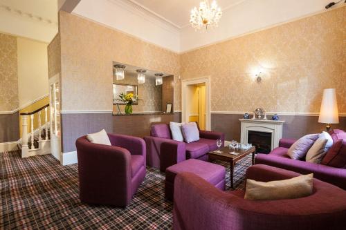 a living room with purple chairs and a fireplace at The Hotel Balmoral - Just for Adults in Torquay