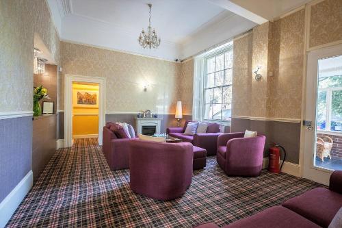 a living room with purple chairs and a fireplace at The Hotel Balmoral - Just for Adults in Torquay