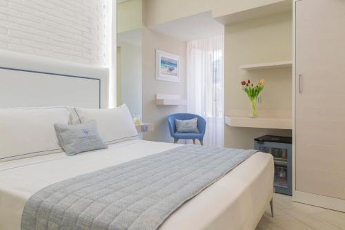 a bedroom with a white bed and a blue chair at Townhouse Tropea in Tropea