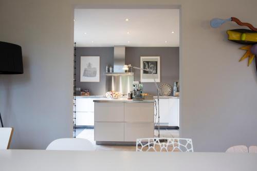 - une cuisine avec des placards blancs et un grand miroir dans l'établissement La Colline des Renards Chambres, à Locmaria-Berrien