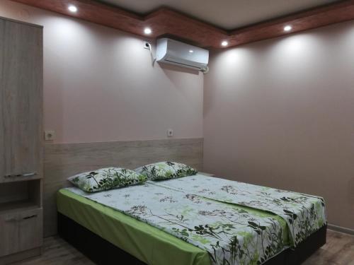 a bedroom with a bed with a green comforter at Къща за гости Мира in Strelcha