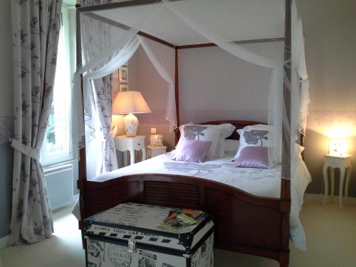 een slaapkamer met een hemelbed met paarse kussens bij GUTKOWSKI Jacqueline in Saint-Philbert-de-Bouaine