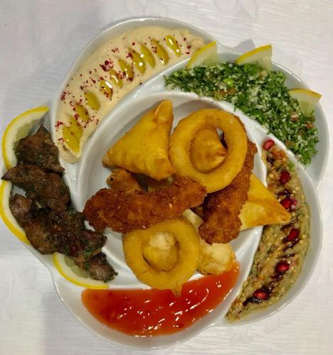 a plate of food with fried onion rings and other foods at Novotel Jazan in Jazan