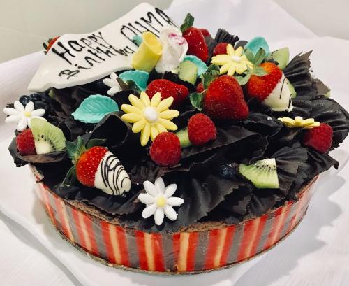 a chocolate cake with strawberries and flowers on top at Novotel Jazan in Jazan