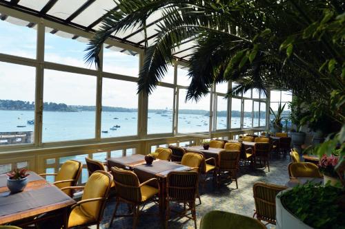 a restaurant with tables and chairs and a view of the water at Logis Hôtel Restaurant le Printania in Dinard