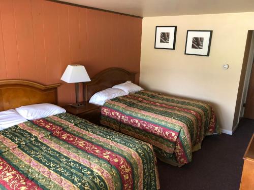 a hotel room with two beds and a lamp at Angola Motel in Angola-on-the-Lake